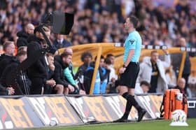 Chris Kavanagh checks the Video Assistant Referee screen to review Manchester City's second goal, scored by John Stones.