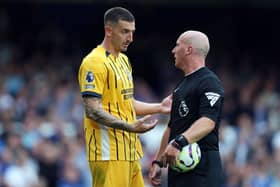 Lewis Dunk of Brighton & Hove Albion interacts with Referee Simon Hooper. (Photo by Carl Recine/Getty Images)