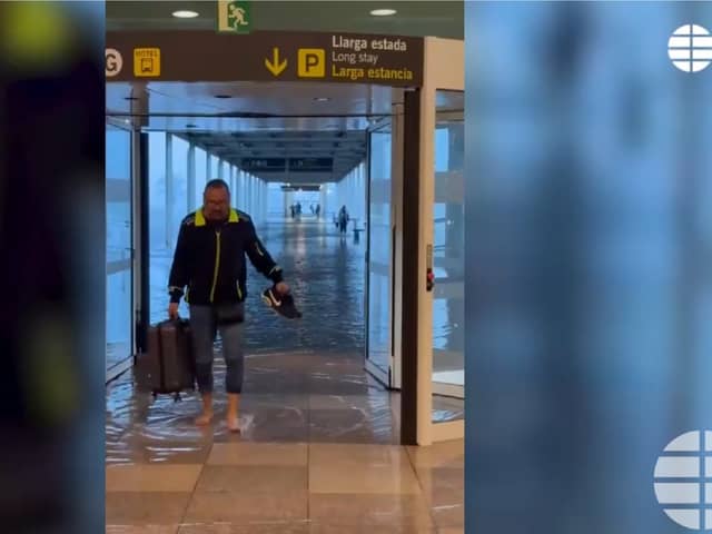Passenger wades through flood water at Barcelona's El Prat airport.