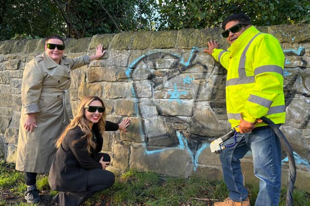 Samantha Owen-Stoddart, Maria Manco, and Con Doc Anand cleaning graffiti on a wall on Grandstand Road, Newcastle, next to the Town Moor