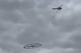 Helicopter carrying large metal circle.