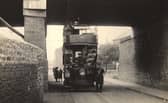 A tram approaching Bell's Close in the early 1900s. A sign on the bridge says 'car passengers must not stand when passing under bridge. It is dangerous to touch the wires.'
