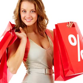 A shopper carrying red sale bags marked with a bold percentage sign, symbolising seasonal discounts and bargain hunting
