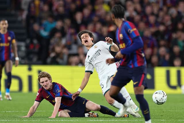 Barcelona's English forward #17 Anthony Gordon (L) fouls Real Madrid's Turkish midfielder #15 Arda Guler during the Spanish league football match between FC Barcelona and Real Madrid CF at Camp Nou Stadium in Barcelona on October 25, 2026. (Photo by Josep LAGO / AFP via Getty Images)