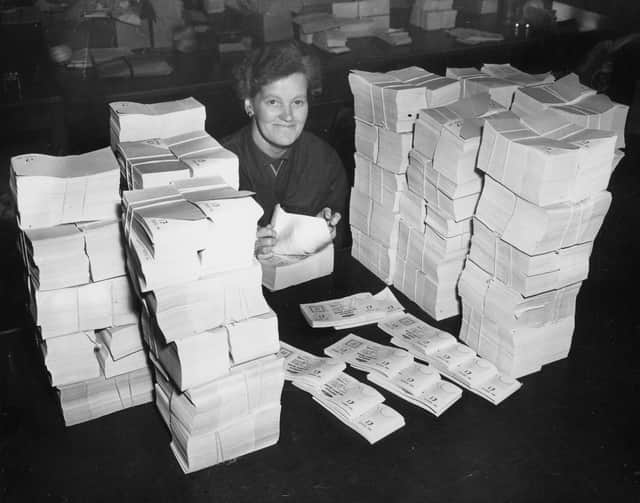 30th October 1956: Evelyn Shaw counting one pound denomination premium bonds at the Post Office distribution centre. (Photo by Central Press/Getty Images)