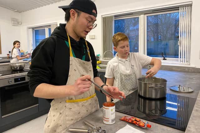 New charity kitchen set to support low income families through high cost of living period. Kids Kabin international volunteer Milo (left) helps children in the new site.