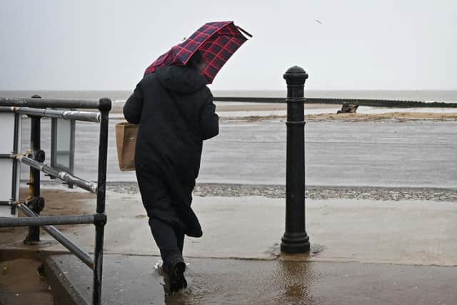 A person struggles with an umbrella in the wind and rain.