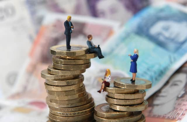 Models of men and women on a pile of coins and bank notes.