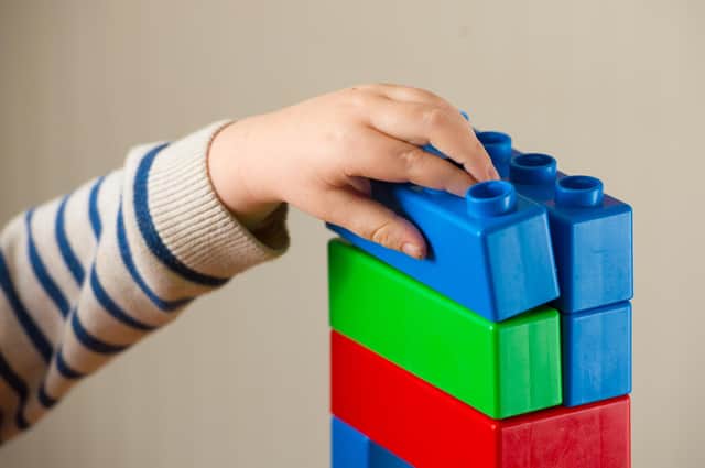 A preschool age child plays with plastic building blocks.