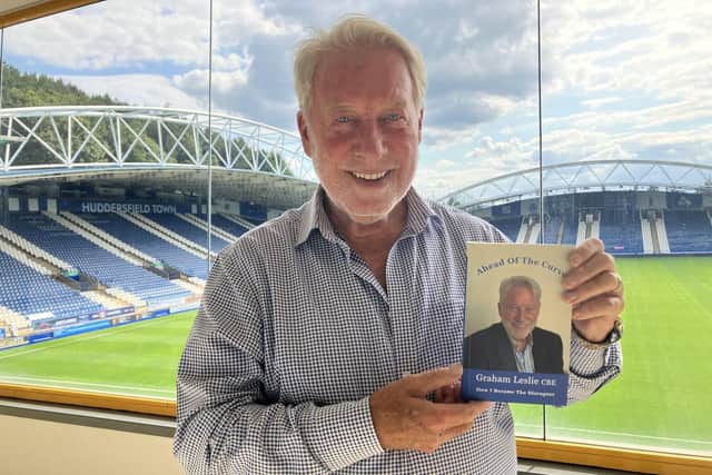Graham Leslie holding a copy of his autobiography Ahead Of The Curve