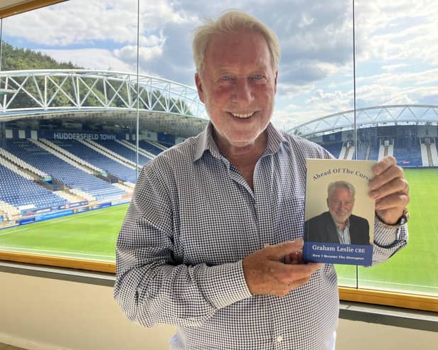Graham Leslie holding a copy of his autobiography Ahead Of The Curve