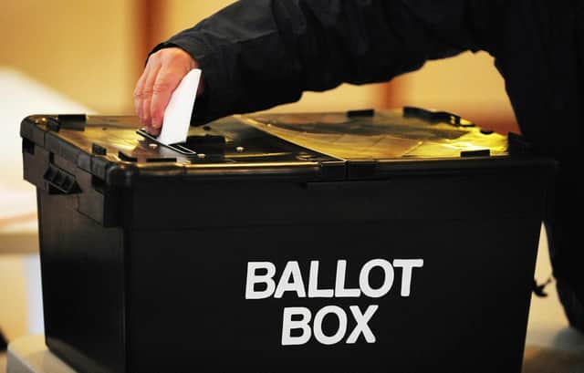 A voter places a ballot paper in the ballot box at the polling station at Market Hall in Swadlincote, Derbyshire, as the General Election got underway across the UK.