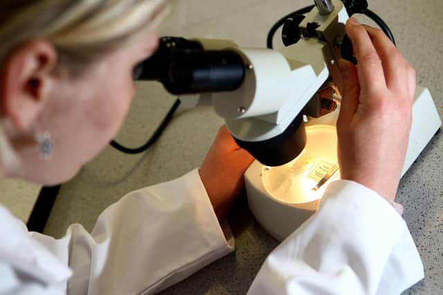 File photo dated 19/05/08 of a woman looking through a microscope. Some 65,400 people every month in England are waiting too long to find out whether they have cancer, according to a new analysis from Cancer Research UK. Issue date: Monday May 9, 2022.