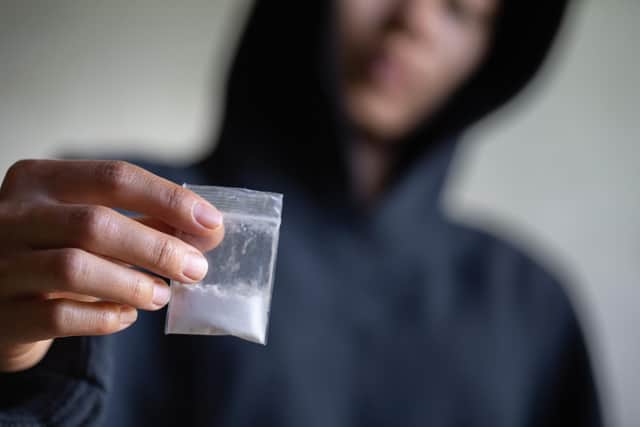 Hand of addict man holding cocaine or heroine