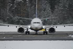 A plane on an airport runway surrounded by snow