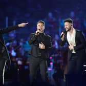 Howard Donald and Gary Barlow of Take That, perform with Callum Scott (right) on stage during the Coronation Concert