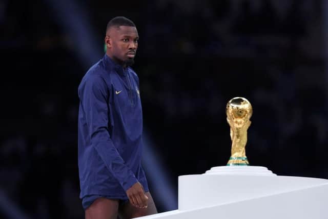 Marcus Thuram of France walks past the FIFA World Cup Qatar 2022 Winner's Trophy during the awards ceremony after the FIFA World Cup Qatar 2022 Final match between Argentina and France at Lusail Stadium on December 18, 2022 in Lusail City, Qatar. (Photo by Clive Brunskill/Getty Images)