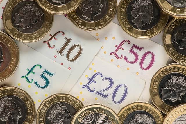 UK five pound, ten pound, twenty pound and fifty pound notes with one pound coins.