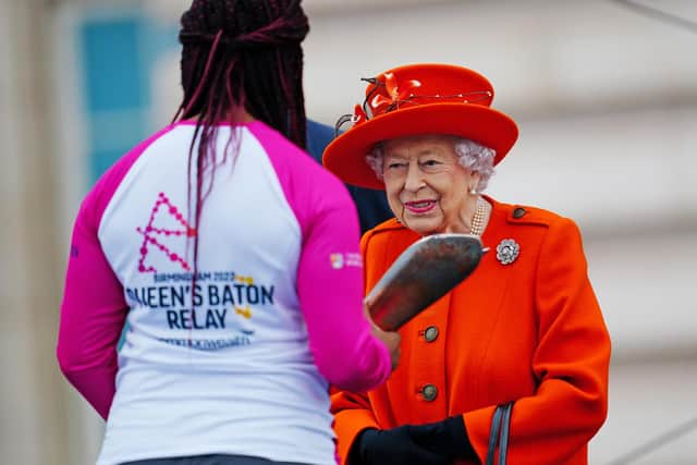 LONDON, ENGLAND - OCTOBER 07: Queen Elizabeth II passes her baton to the baton bearer, British parasport athlete Kadeena Cox, during the launch of the Queen's Baton Relay for Birmingham 2022, the XXII Commonwealth Games at Buckingham Palace on October 7, 2021 in London, England. The Queen and The Earl of Wessex are Patron and Vice-Patron of the Commonwealth Games Federation respectively. (Photo by Victoria Jones - WPA Pool/Getty Images)
